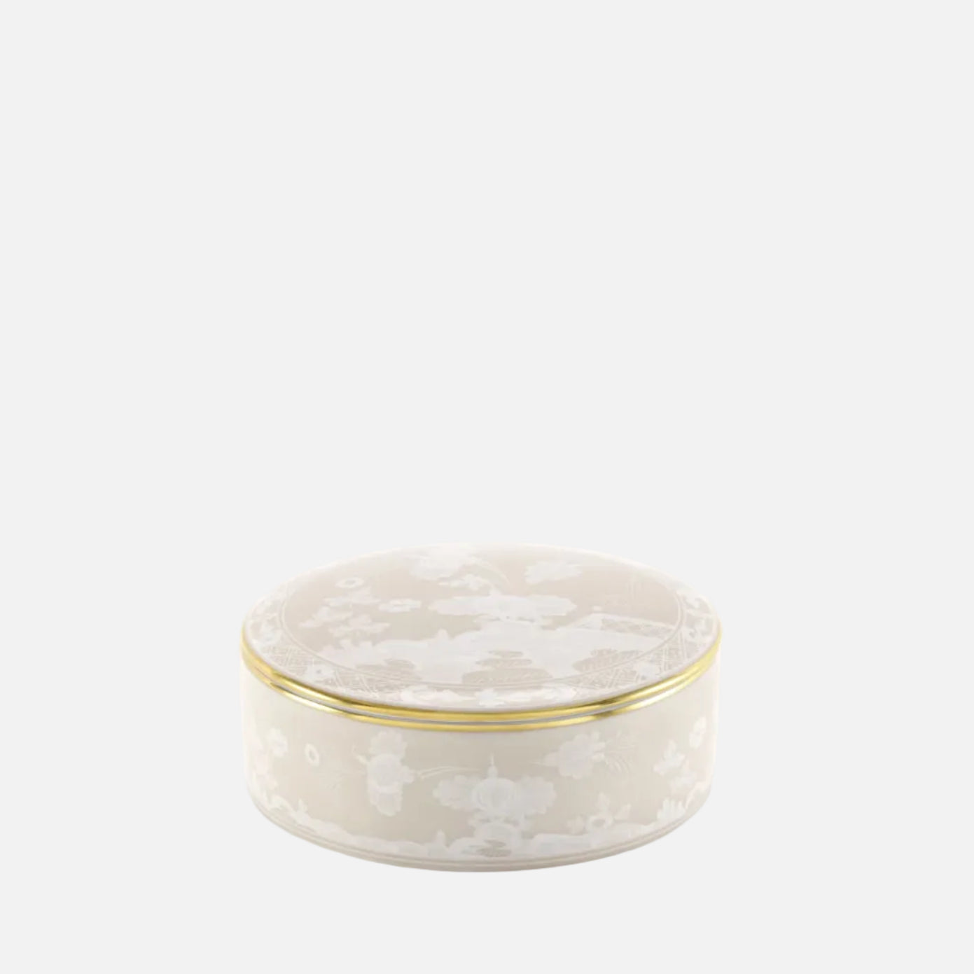 A small round ceramic box with a lid, featuring a white floral pattern on a warm cream background and a thin gold trim around the rim, set against a plain white background.