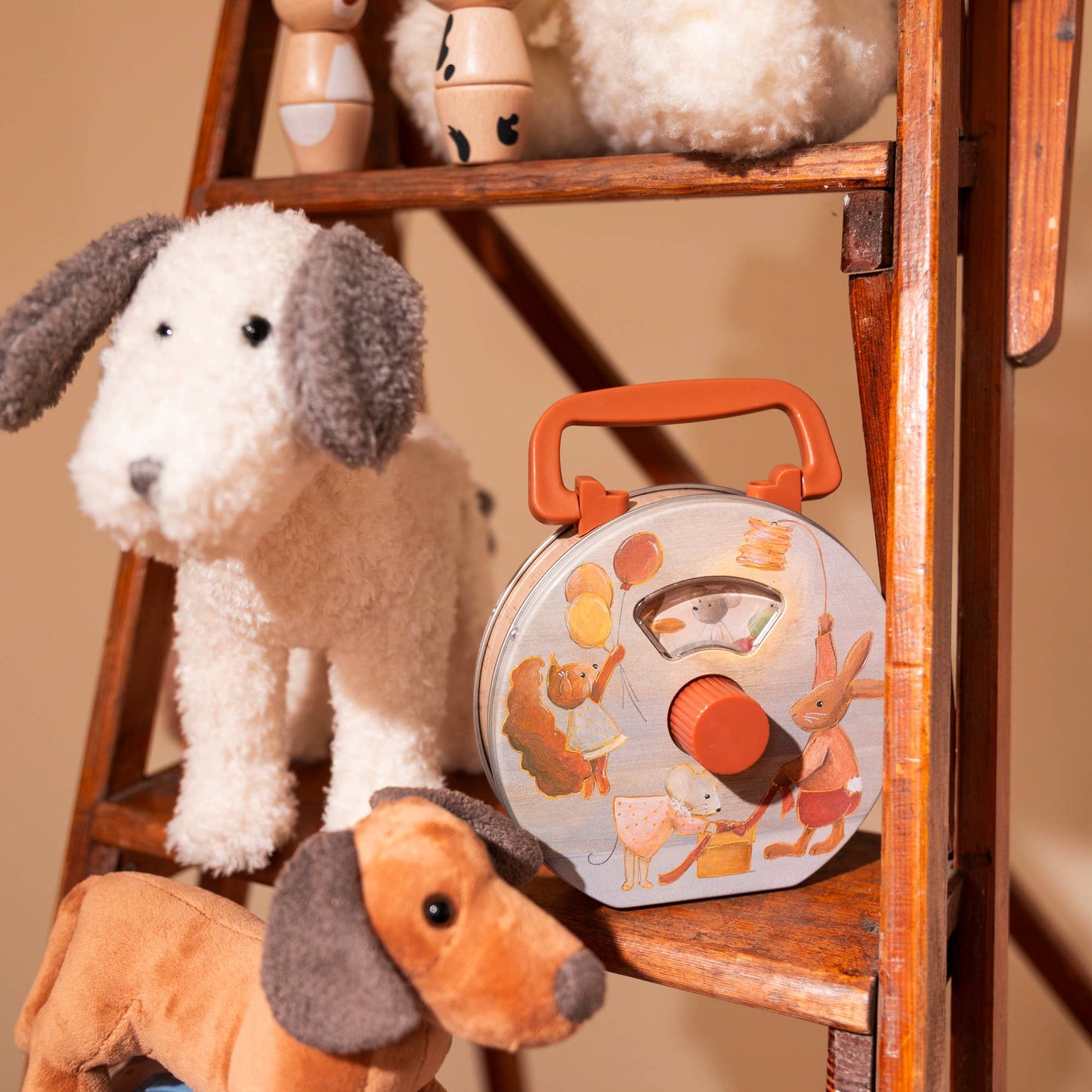 Stuffed dog toys with a round wooden toy on a wooden ladder