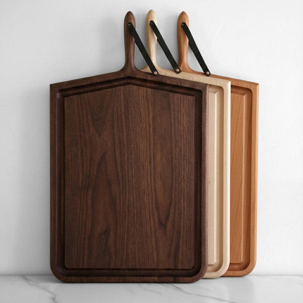Three wooden cutting boards with handles on a light gray background