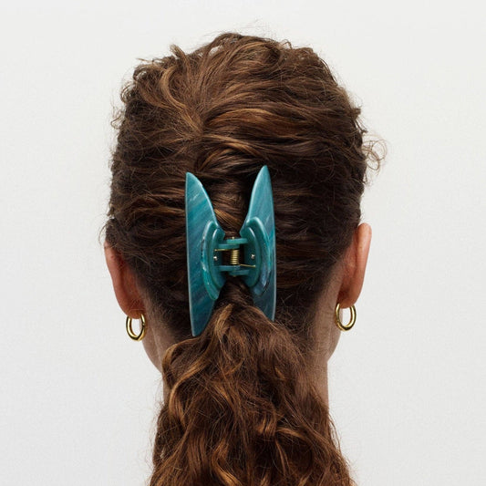 Teal hair clip in a person's hair on a white background
