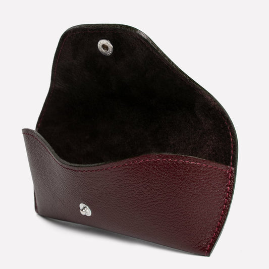 Brown leather cardholder with a silver emblem on a light gray background