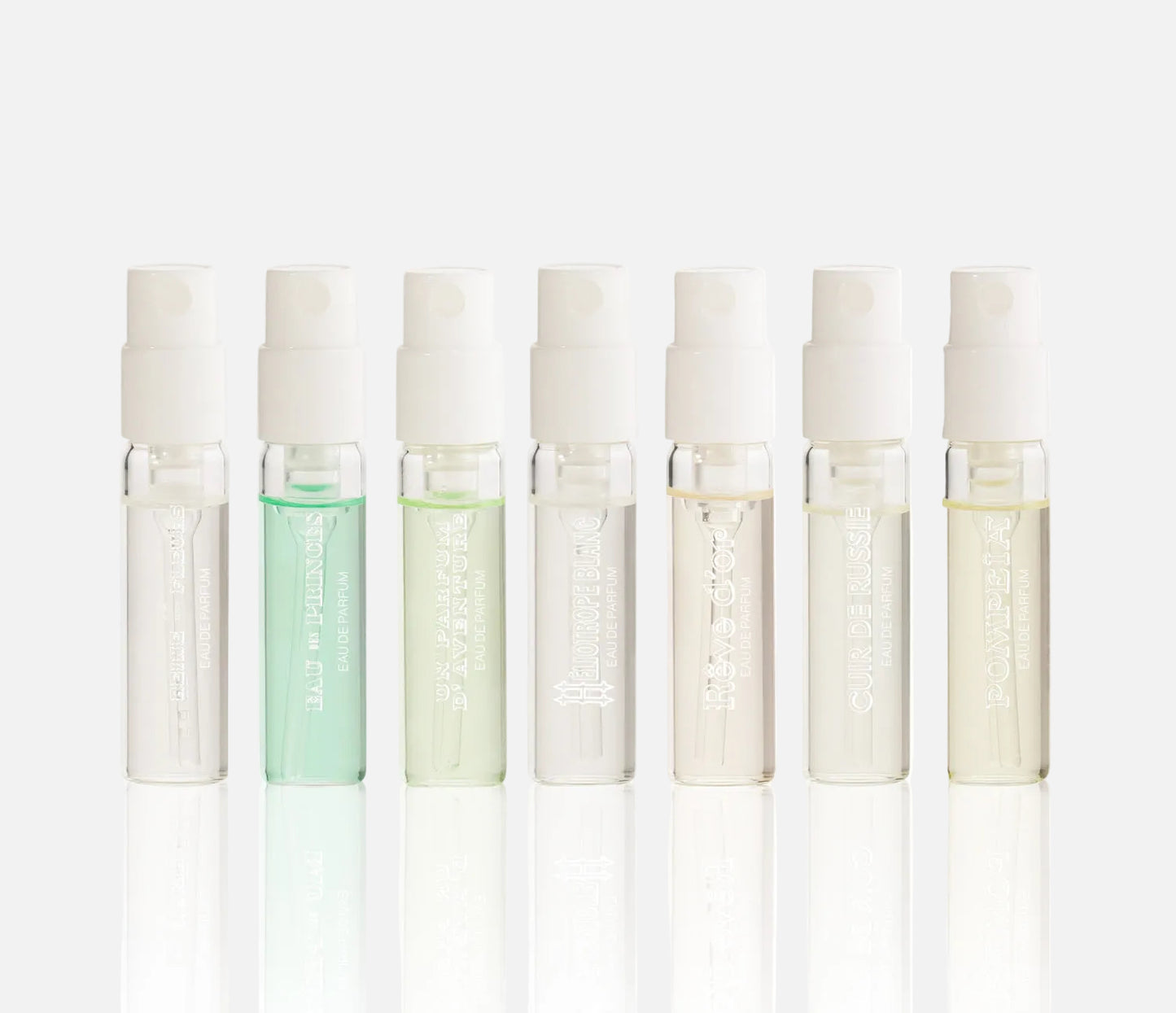 Set of eight small glass bottles with white caps on a white background