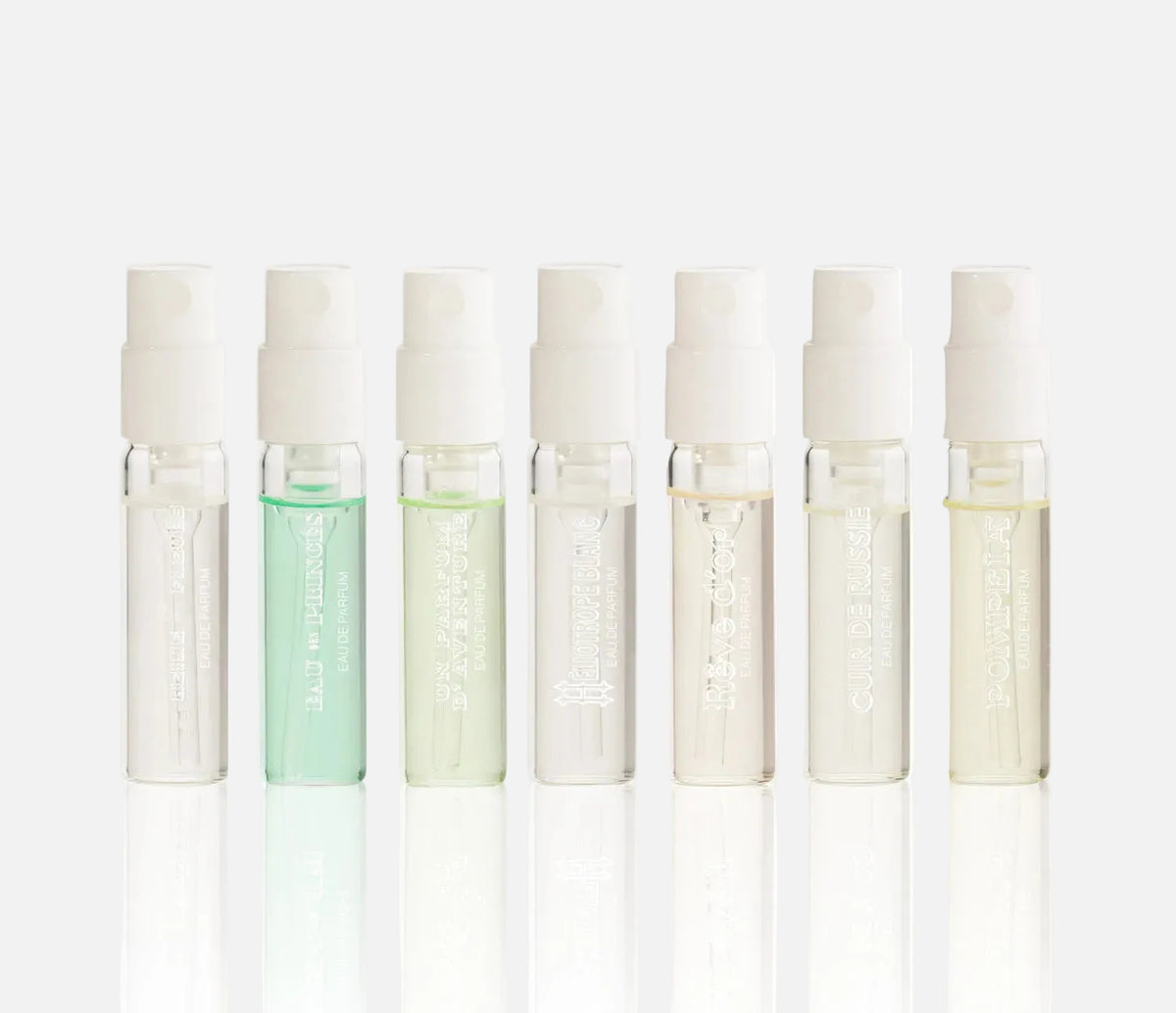 Set of eight small glass bottles with white caps on a white background