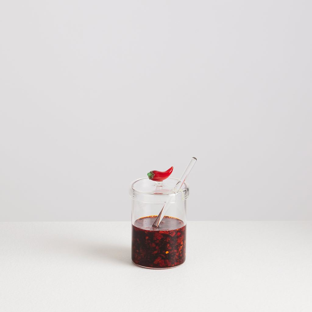 Glass jar with red liquid and a straw on a white background