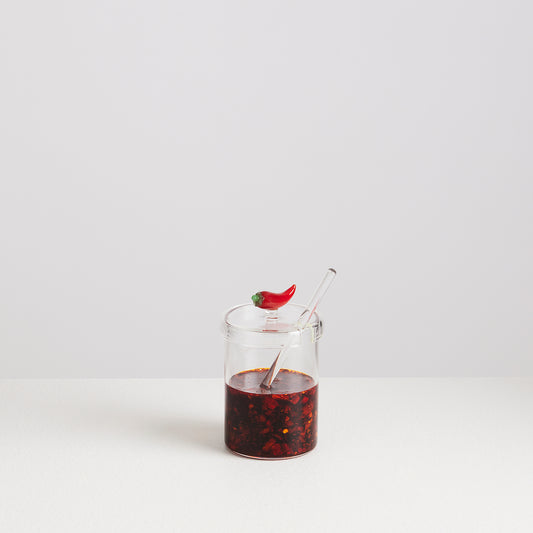 Glass jar with red liquid and a straw on a white background