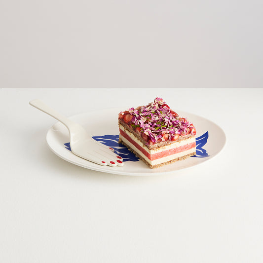 Sliced layered dessert on a decorative plate with a white background