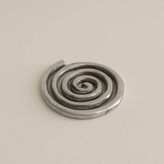 Metallic spiral object on a beige background