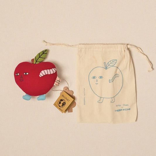 Red apple-shaped toy with a green leaf, a small wooden block, and a beige drawstring bag with an apple illustration on a beige background.