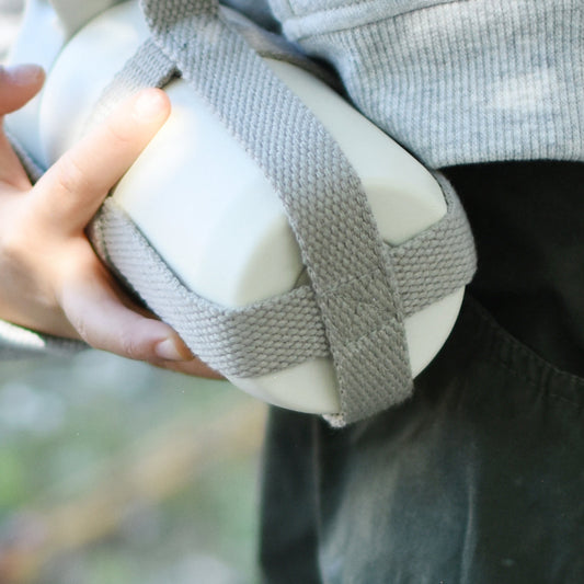 Person holding a white ball with gray straps against a blurred background