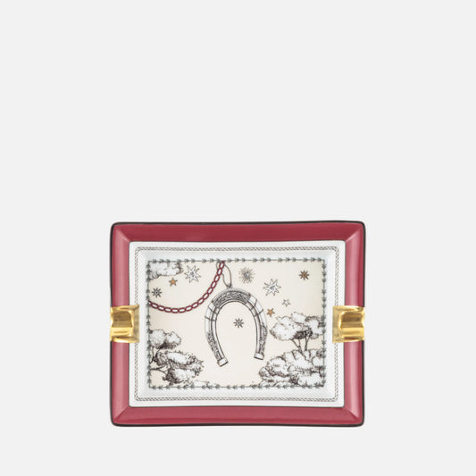 A square decorative tray with a deep red border, gold-toned side accents, and a central cream-colored panel featuring a black and red toile de Jouy-style illustration of a horseshoe, stars, and winter motifs.