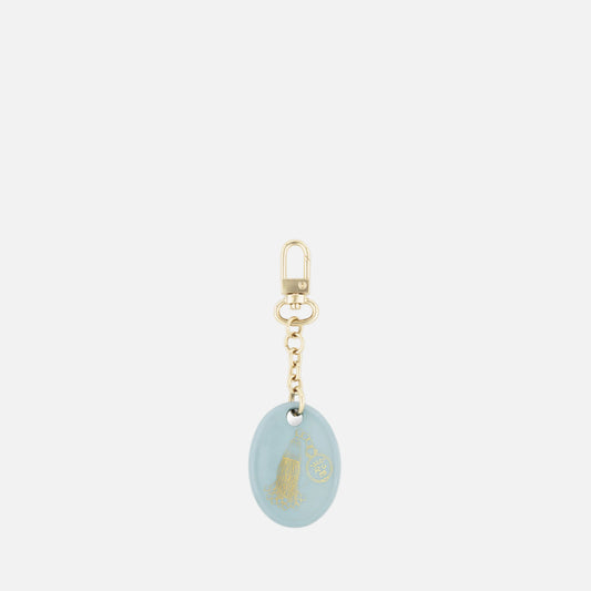A light blue oval keychain charm with a gold foil illustration of a woman in a flowing dress, attached to a gold-tone chain and lobster clasp, shown on a plain white background.