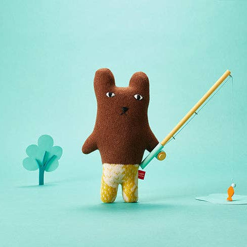Stuffed animal resembling a bear with a fishing rod on a light blue background