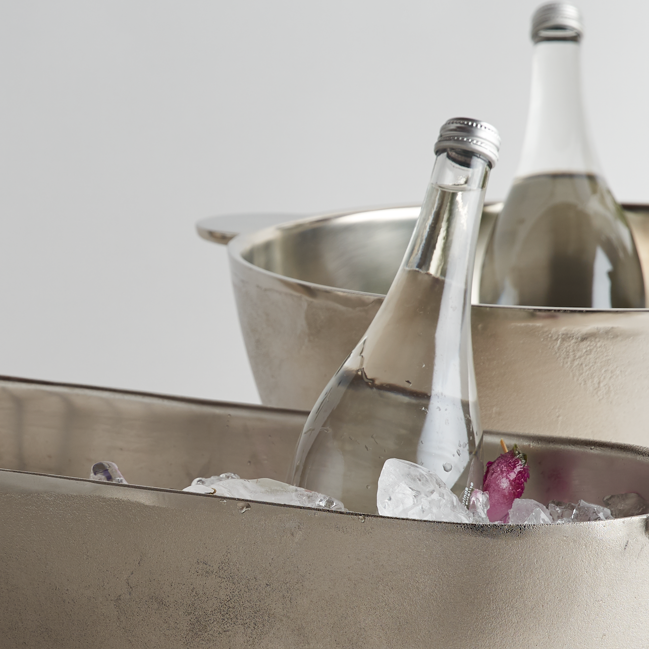 Beverage bottles in metal ice buckets with a white background