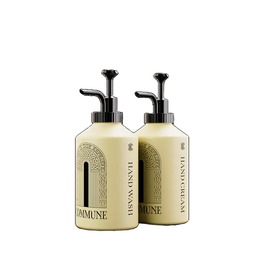 Two cream-colored pump bottles of Commune Hand Wash and Hand Cream with black pumps, shown on a plain white background.