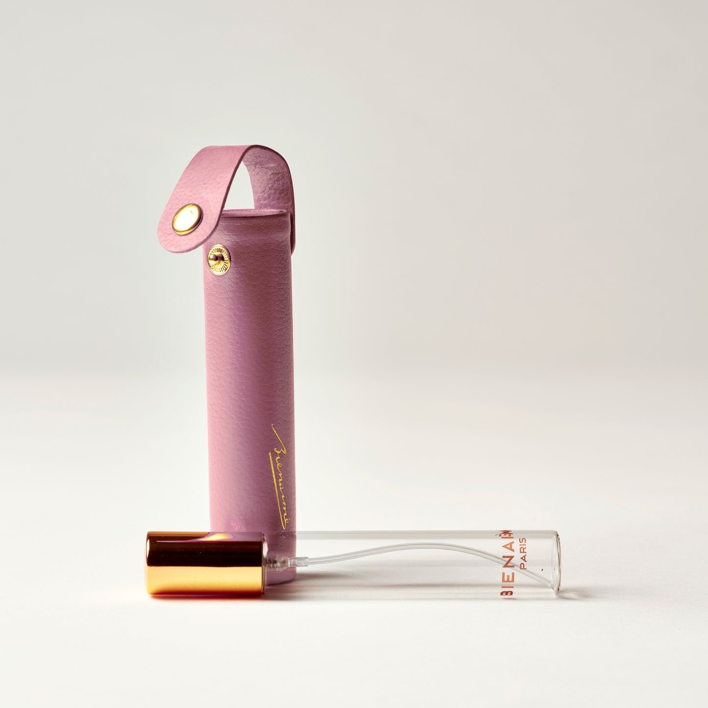 Pink perfume bottle with gold cap on a light gray background