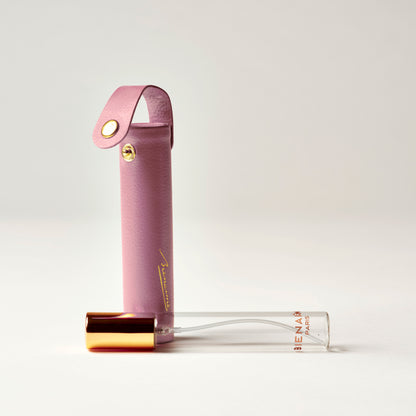 Pink perfume bottle with gold cap on a light gray background