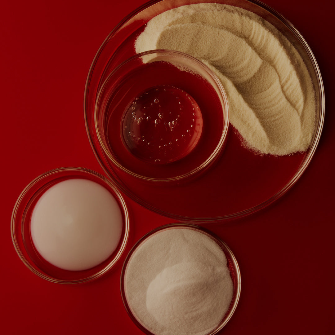Four small glass containers with different colored powders on a red background