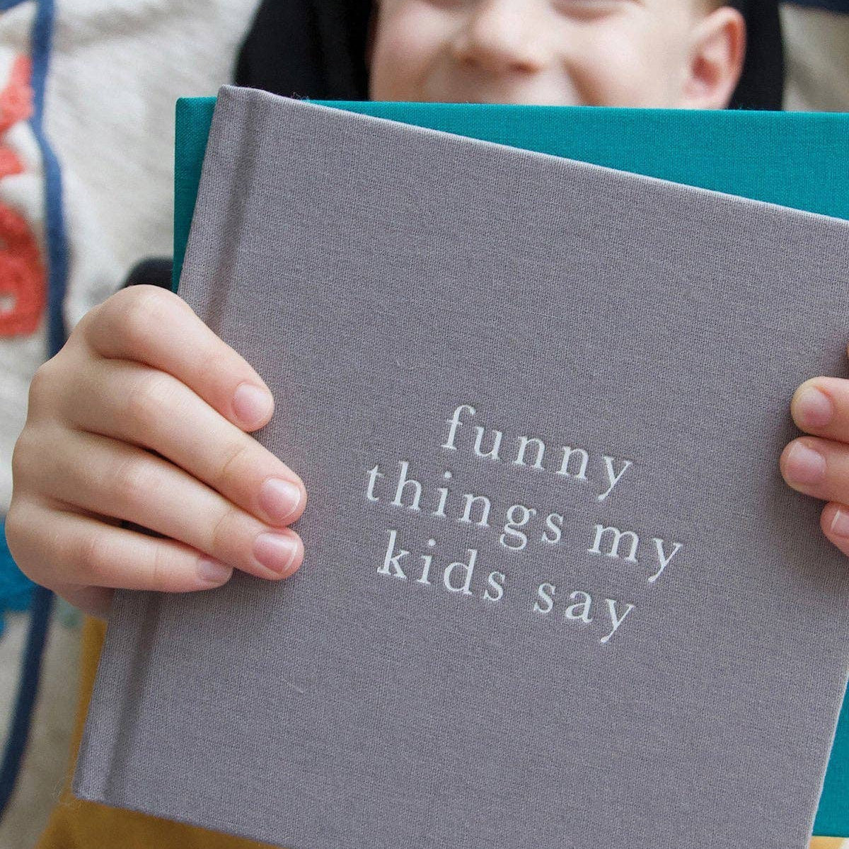 Book titled 'funny things my kids say' held by a child