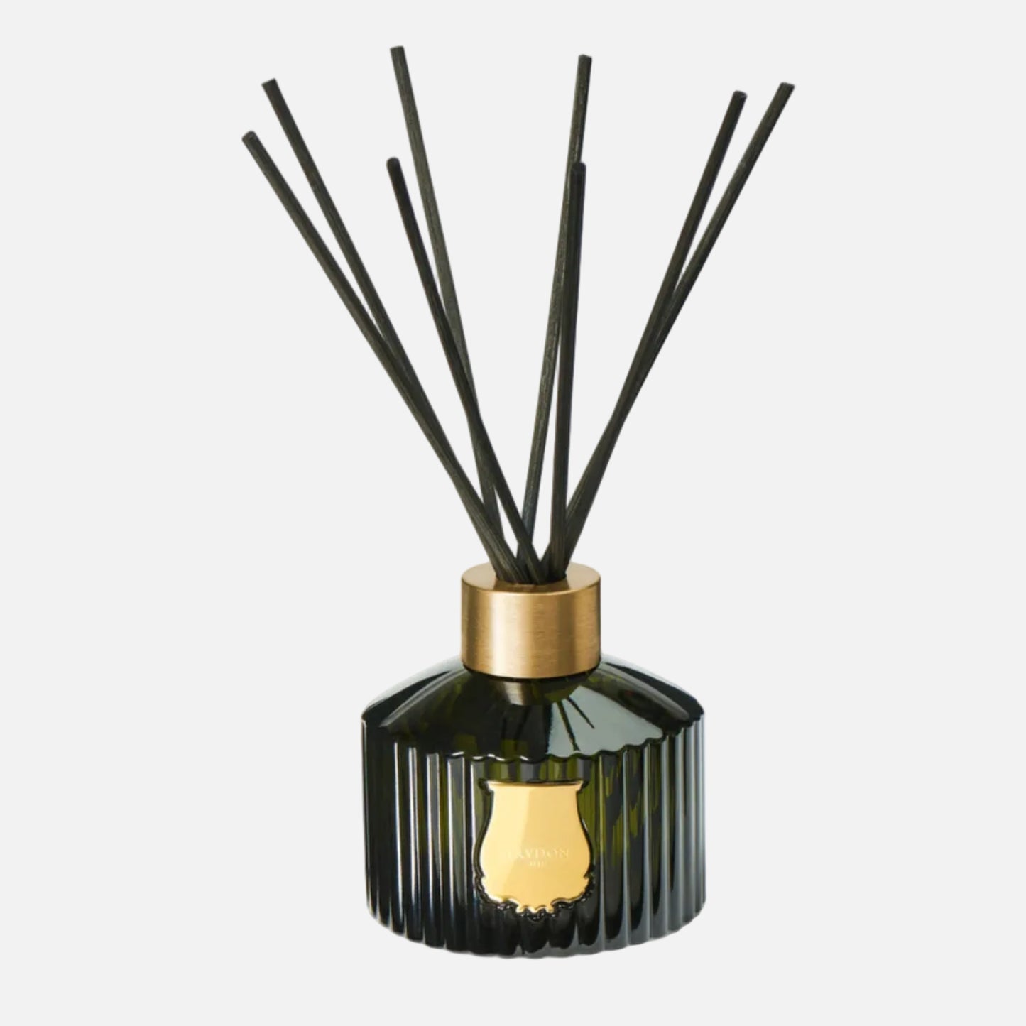 Decorative diffuser with black sticks and gold cap on a white background
