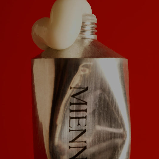 Bottle with a white cap on a red background, featuring the brand 'MENNE'.