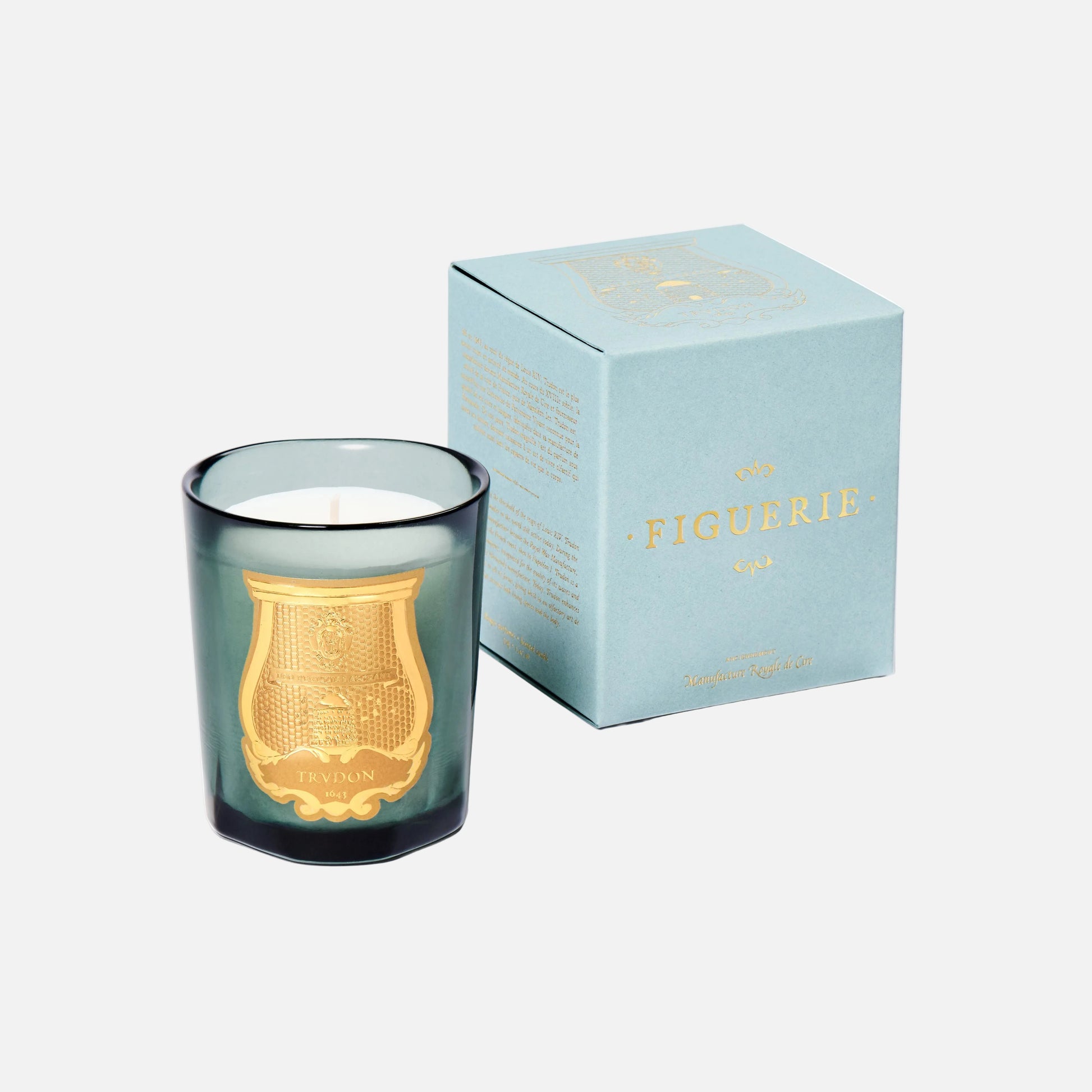 Green candle with gold emblem and matching box on a white background