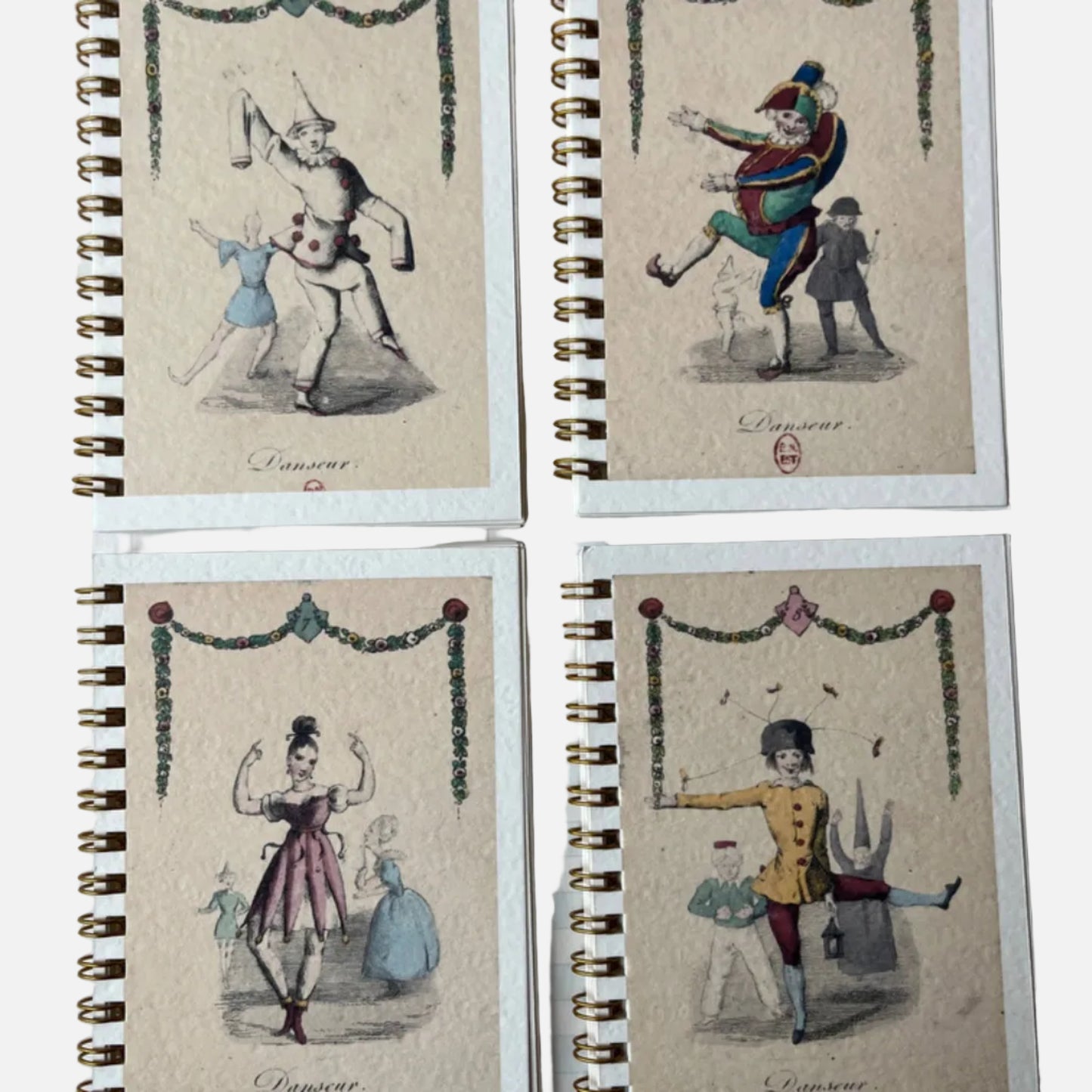 Four spiral-bound notebooks with vintage-style illustrations on a checkered surface.