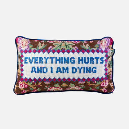 Decorative pillow with embroidered text 'Everything hurts and I am dying' on a white background