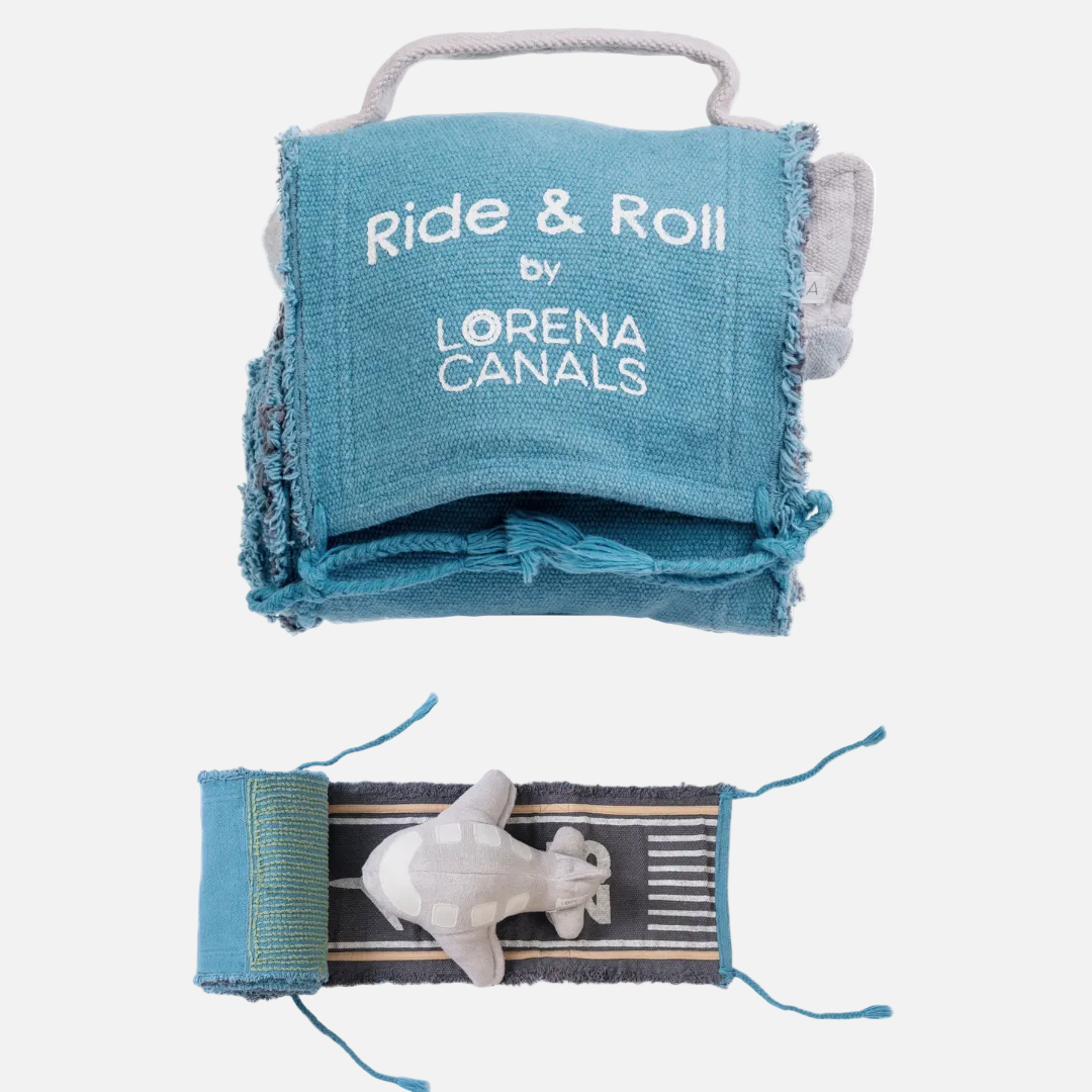 A handmade denim dog toy shown from two angles on a white background. The top view shows a blue denim pouch with a handle, frayed edges, and white embroidered text reading 'Ride & Roll by LORENA CANALS'.
