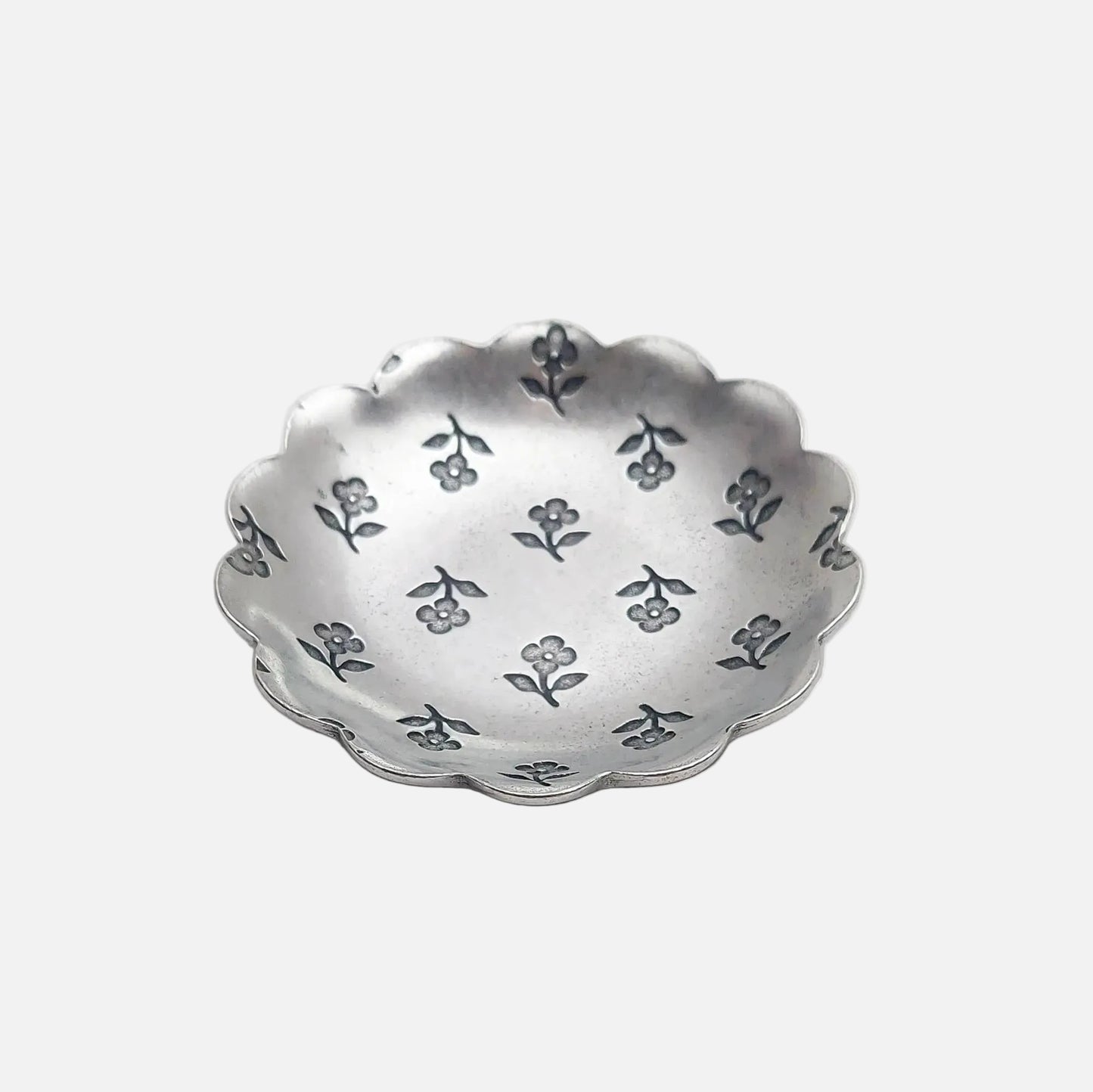 Silver decorative bowl with floral patterns on a light gray background