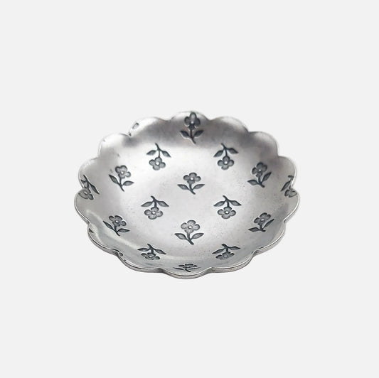 Silver decorative bowl with floral patterns on a light gray background
