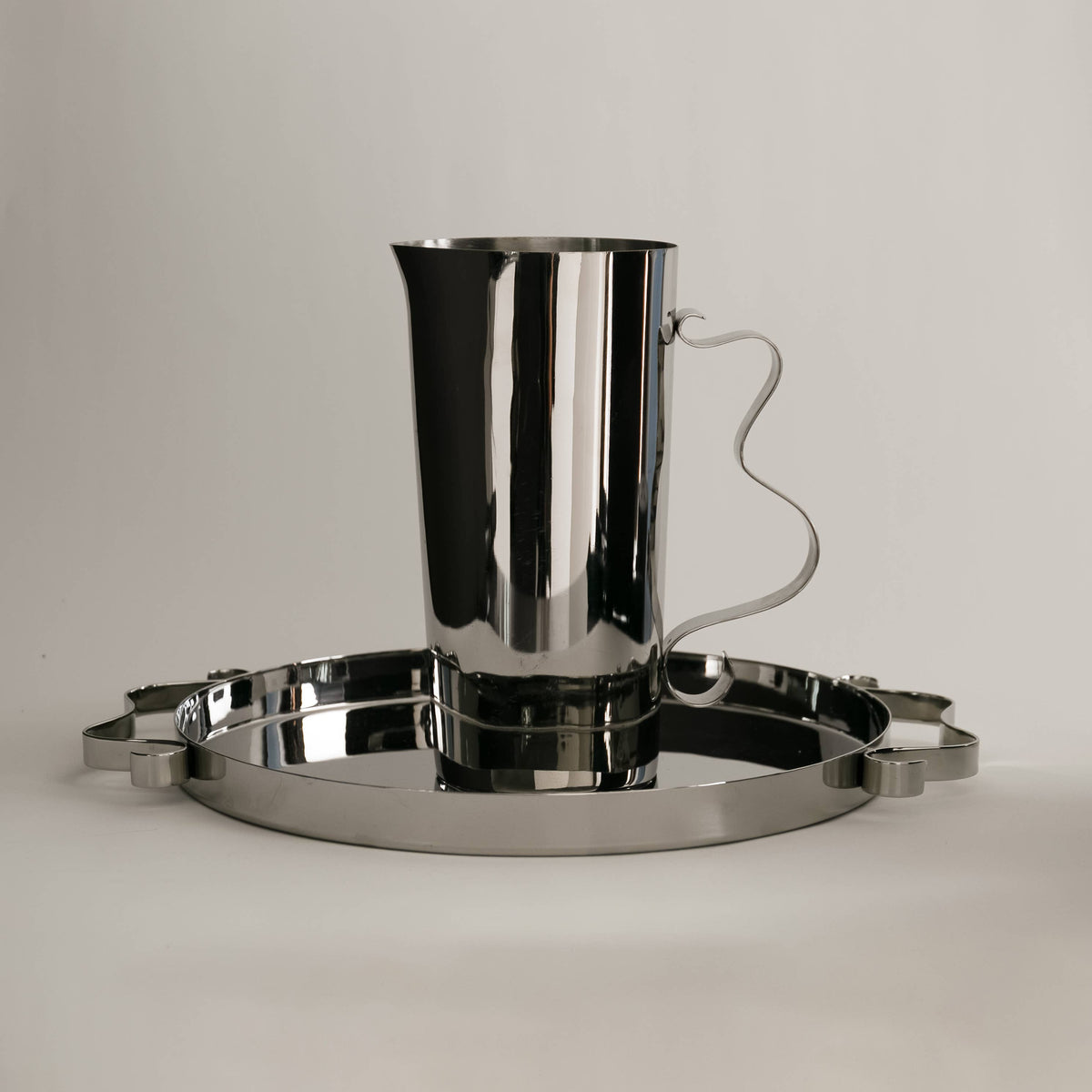 Silver pitcher and tray set on a light gray background