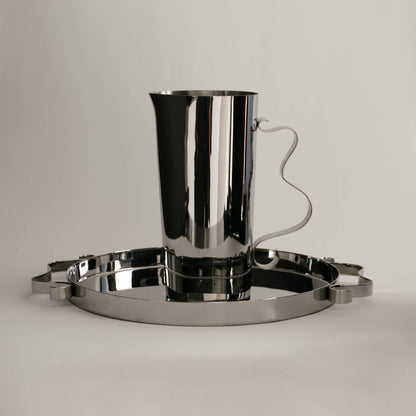 Silver pitcher and tray set on a light gray background