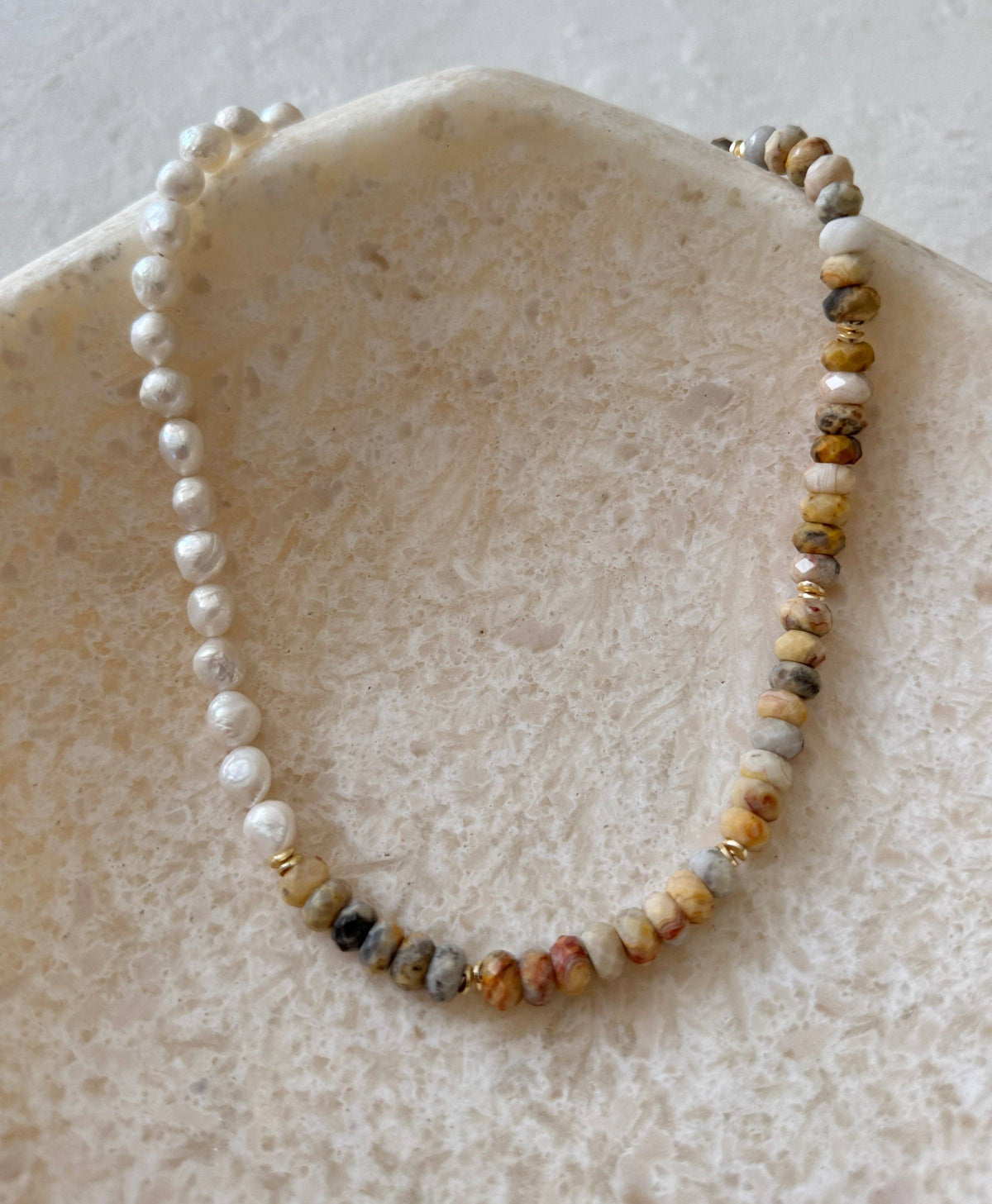 Necklace with pearls and multicolored beads on a stone surface