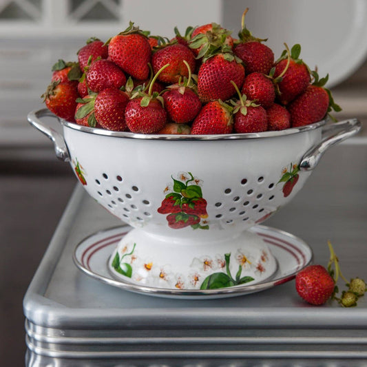White colander filled with strawberries on a decorative surface