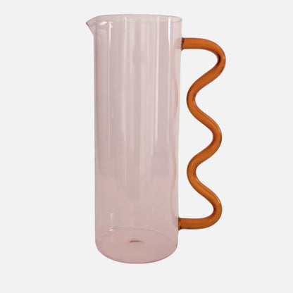 Pink glass pitcher with a wavy wooden handle on a light beige background