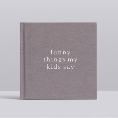 A hardcover book with a textured gray cover and white text reading 'funny things my kids say', photographed against a light gray background.