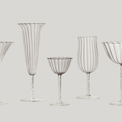 Set of clear glassware including flutes and goblets on a light gray background