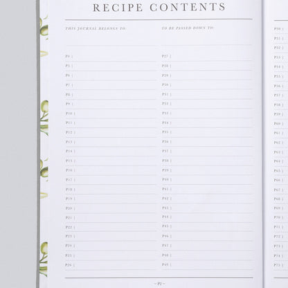 An open recipe journal or planner showing printed recipe contents pages with lined fields and decorative green leaf illustrations along the left margin, photographed on a light gray background.
