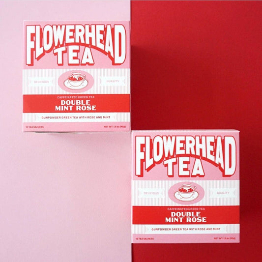 Two boxes of Flowerhead Tea Double Mint Rose tea arranged on a split pink and red background.