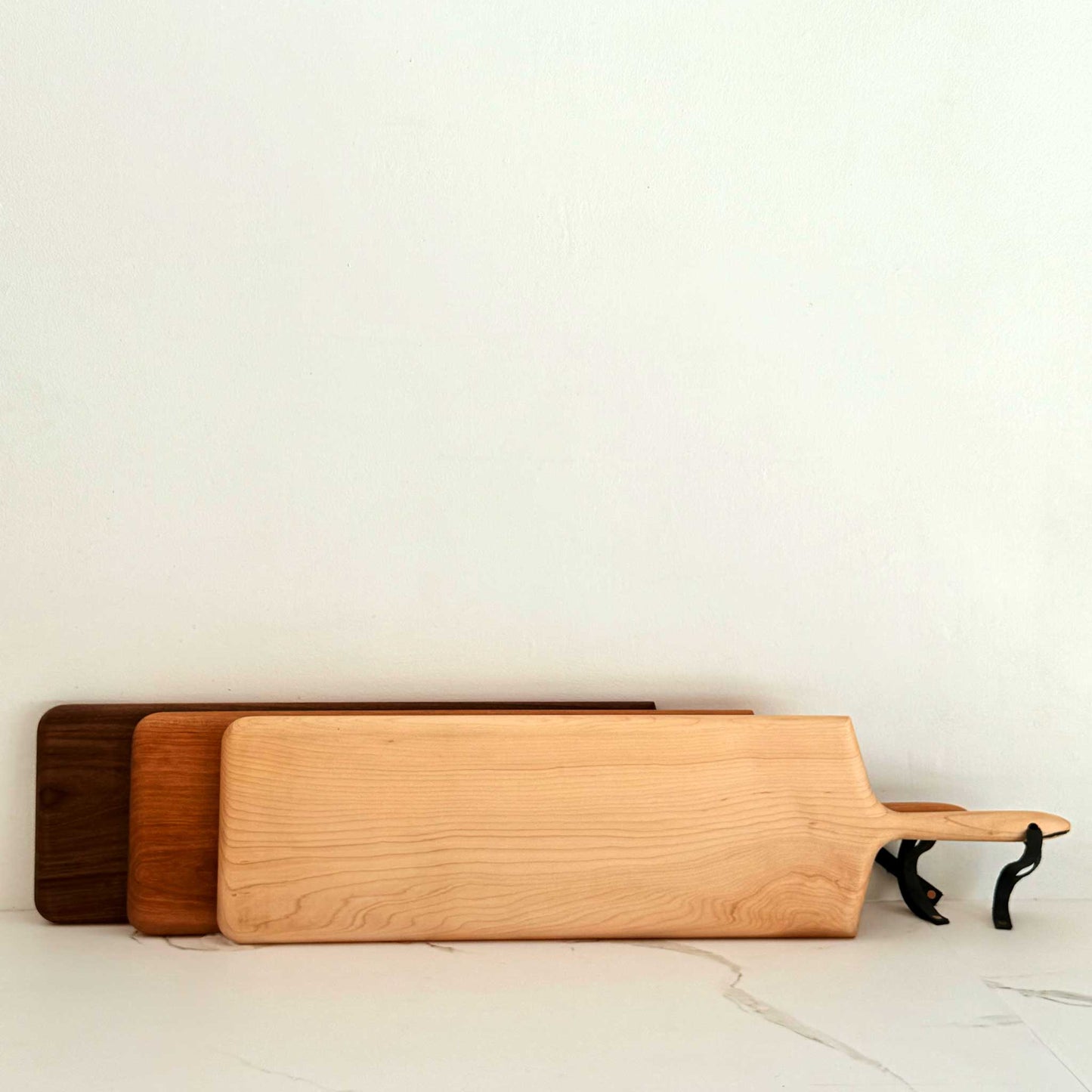 Three wooden cutting boards of different sizes on a light surface.