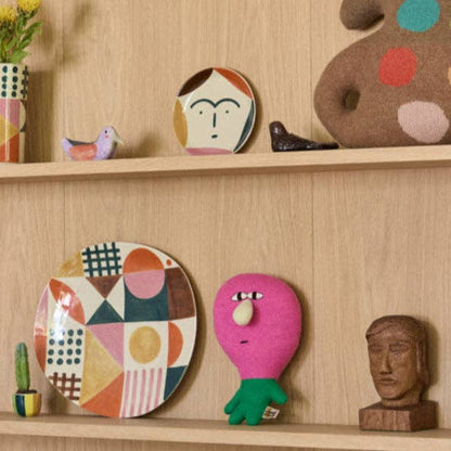 Decorative items including plates, a plush toy, and a wooden sculpture on a wooden shelf.