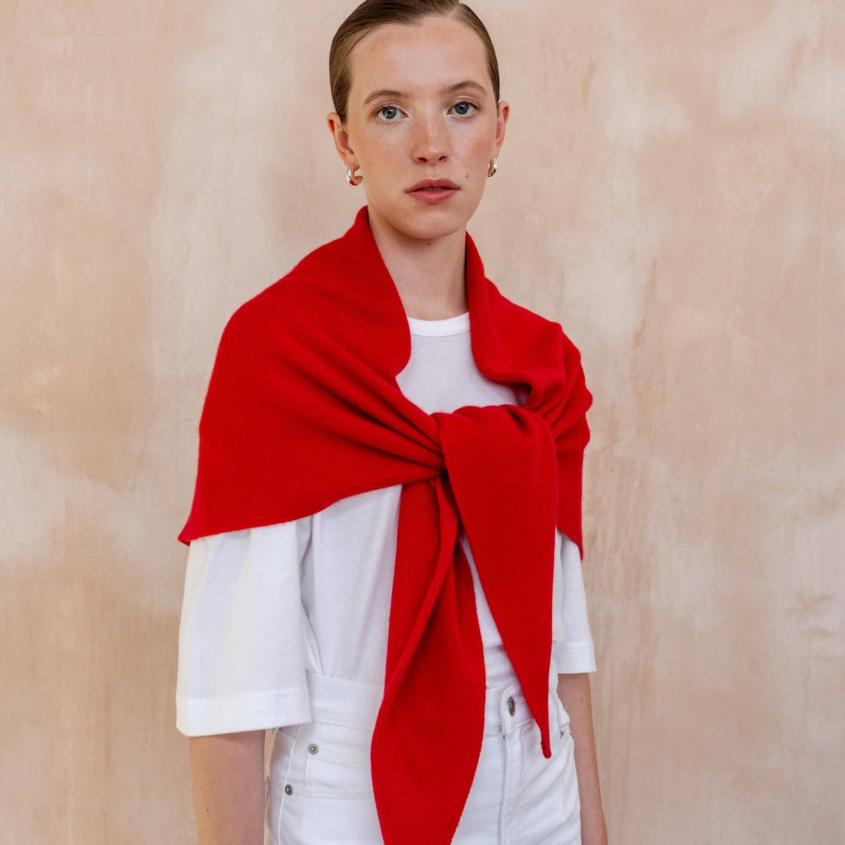 Person wearing a red scarf against a beige background