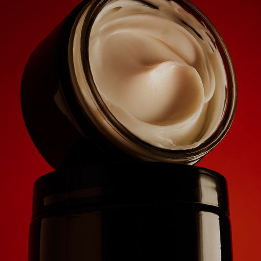 Black jar of cream with a red background