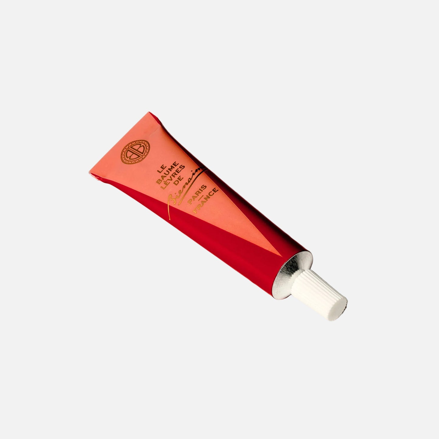 Red cosmetic tube with white cap on a light gray background
