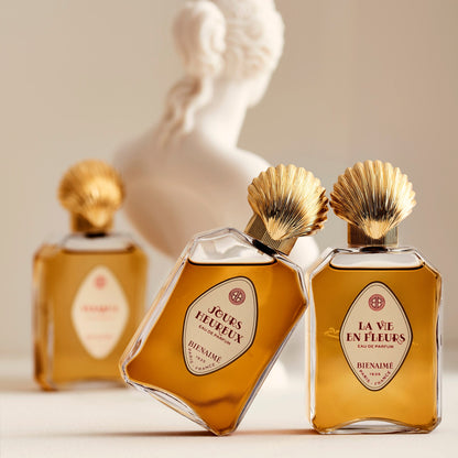 Three perfume bottles with gold caps on a neutral background