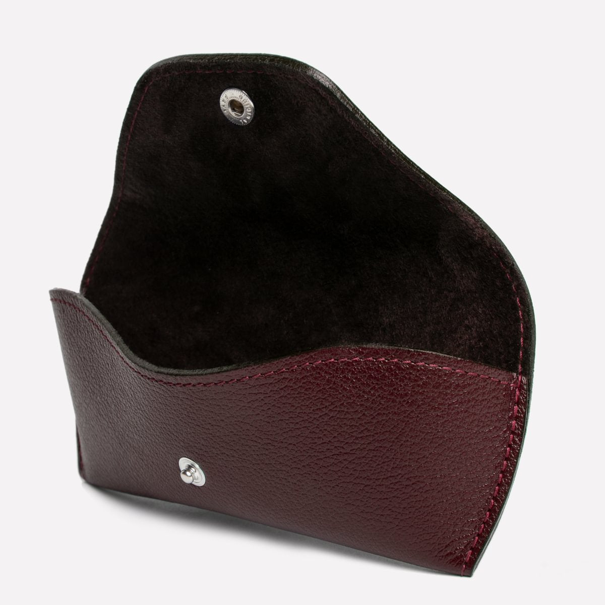 Brown leather cardholder with a silver emblem on a light gray background