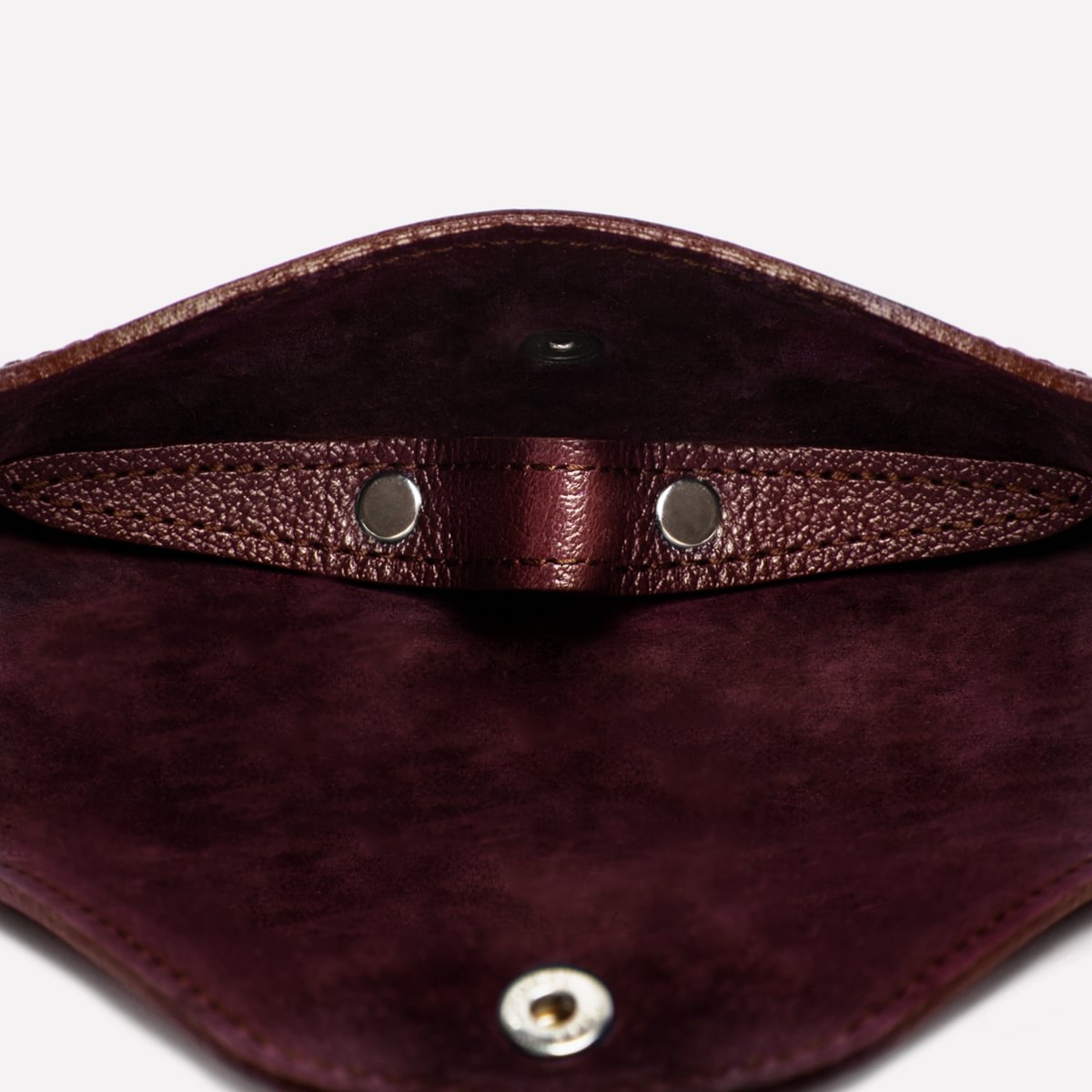 Close-up of a maroon leather pouch with metal clasps on a white background