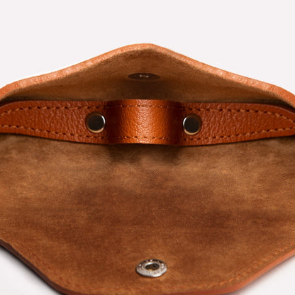 Close-up of a brown leather pouch with metal grommets on a white background