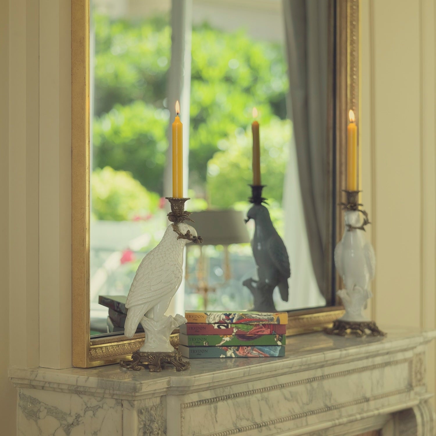 Decorative mirror on a mantelpiece with candles and sculptures