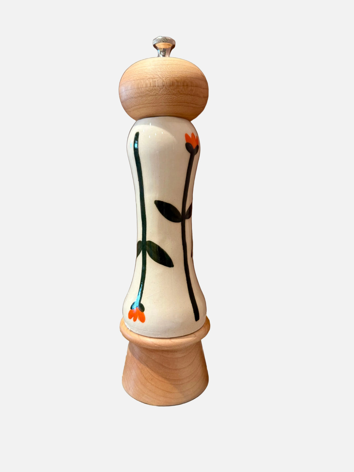 A decorative wooden pepper mill with a cream-colored body featuring a painted green and orange floral vine design, set on a polished agate-patterned surface against a solid brown background.